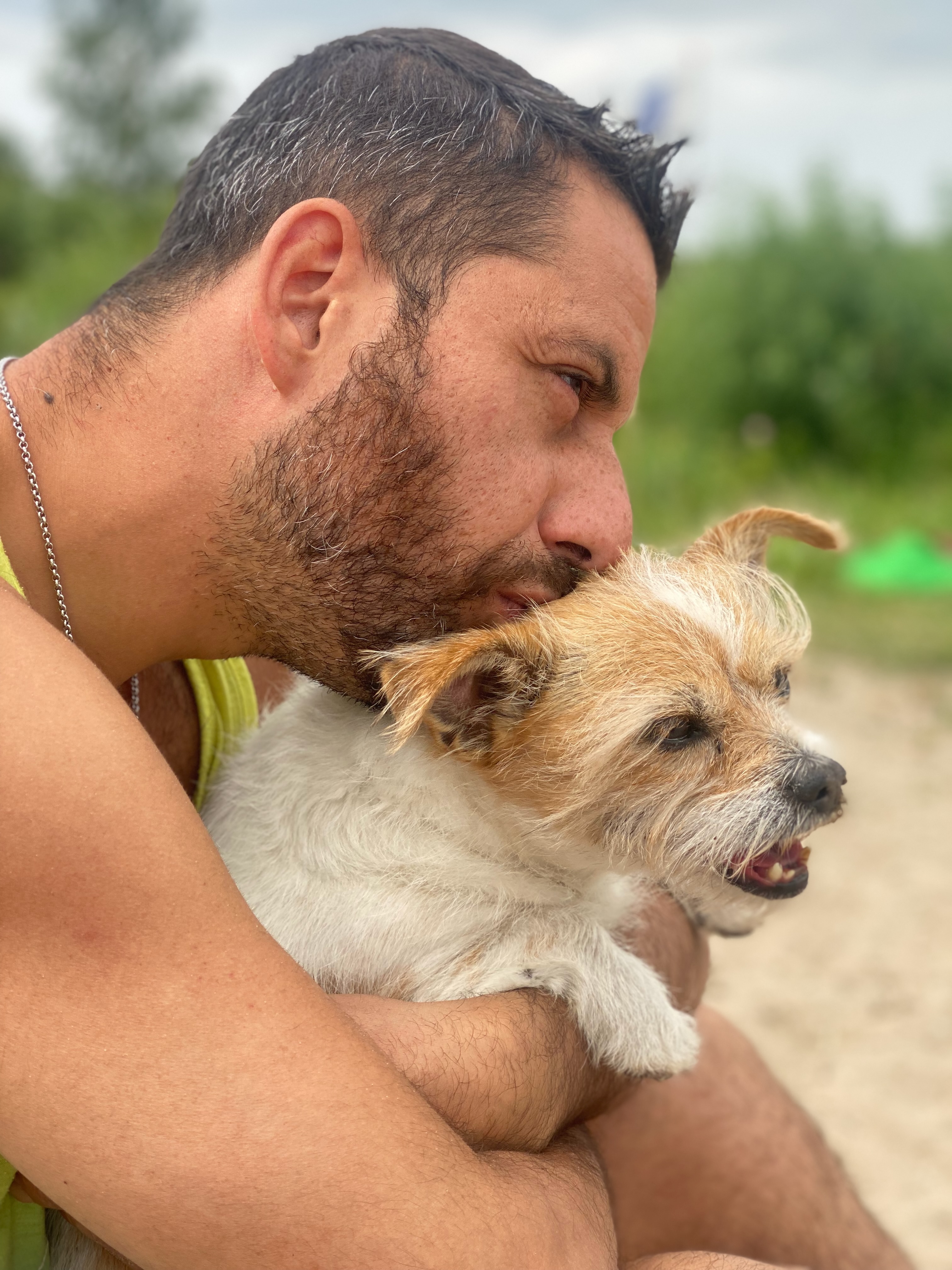 Marek cuddling his tan terrier outdoors